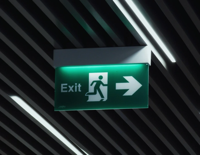 a green exit sign hanging from the ceiling
